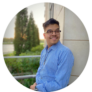 Hashim standing against a wall smiling.